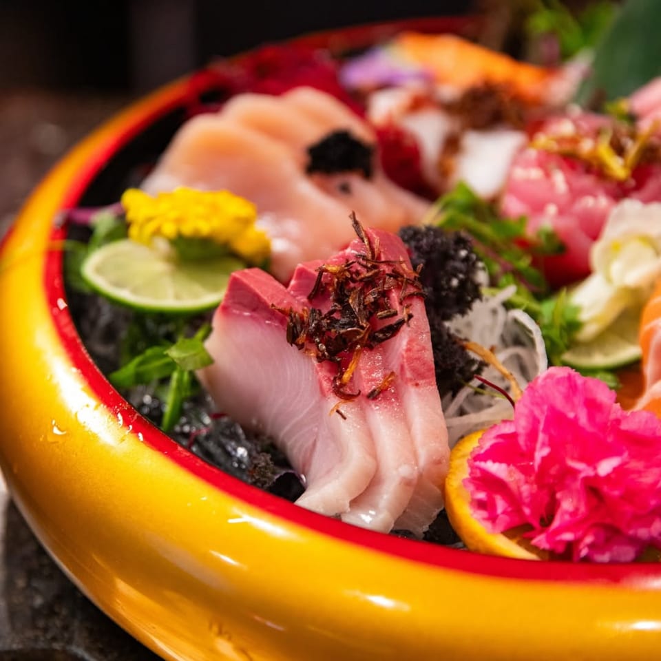 Close-up of a vibrant Shogun Sushi sashimi platter with various fish, garnishes, and edible flowers.