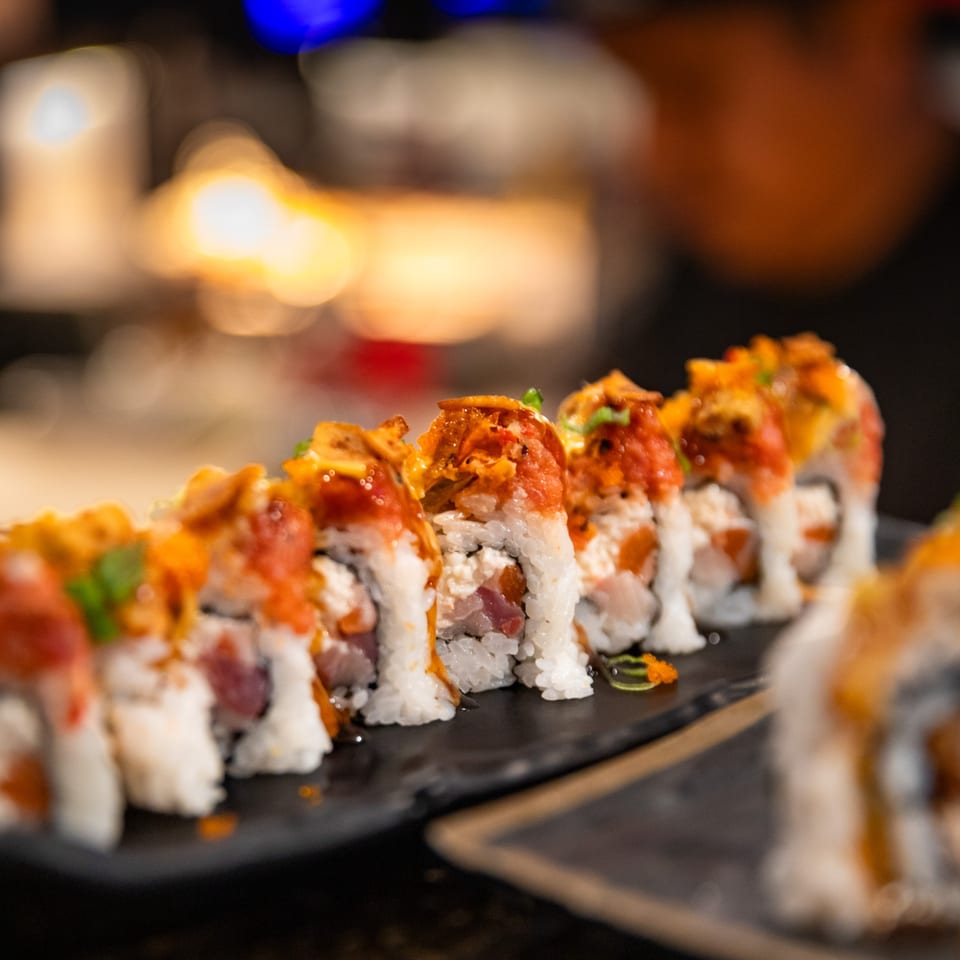 A row of Shogun Sushi's Japanese sushi rolls with spicy toppings on a dark plate.