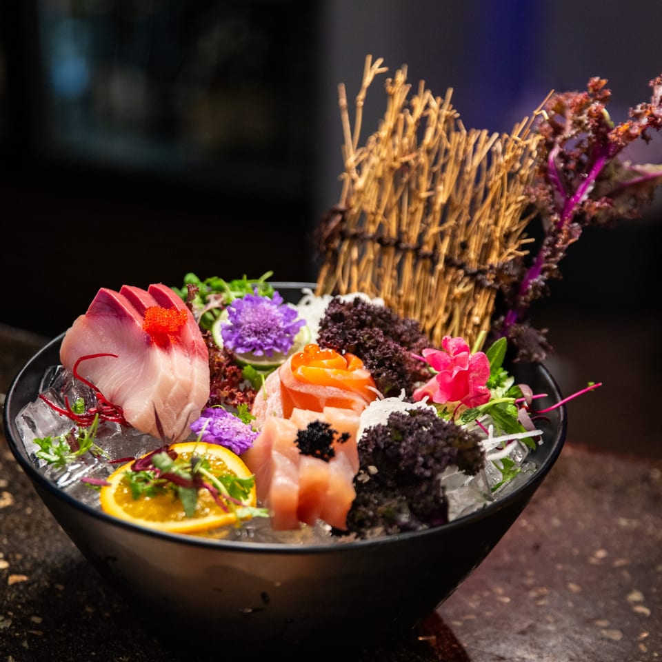 Shogun Sushi's colorful sashimi platter with various fish, roe, and garnishes on ice in a black bowl.